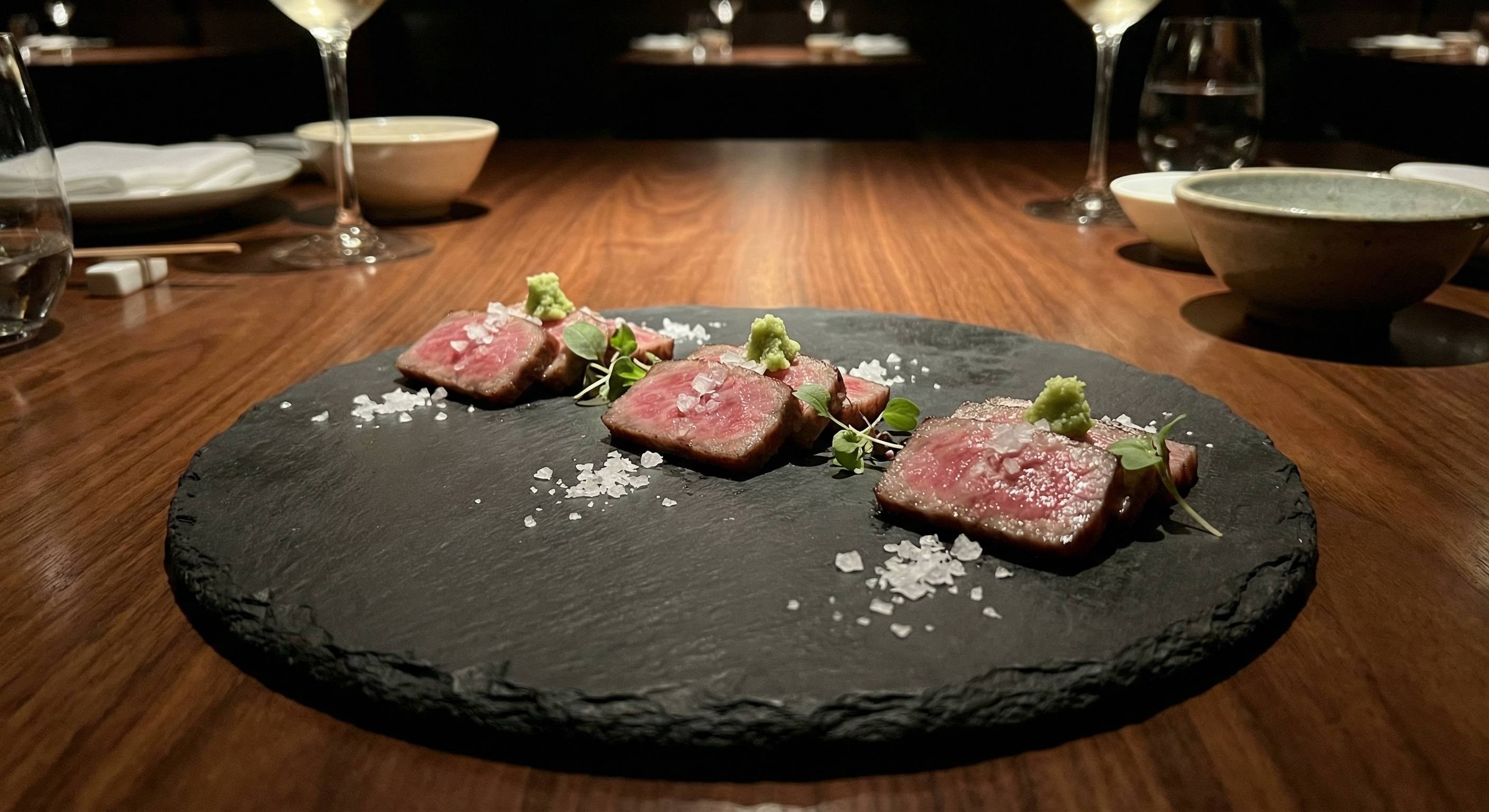 Elegant plated Wagyu tasting portions with seared A5 slices on a dark slate plate